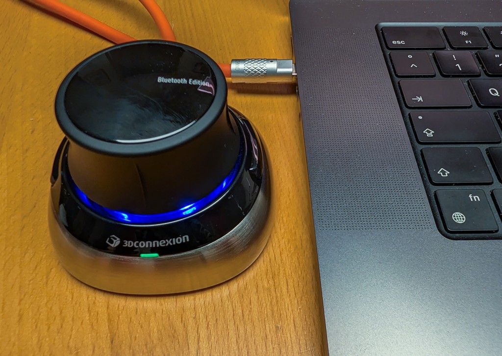 3Dconnexion SpaceMouse Wireless Bluetooth Edition on a desk next to a laptop